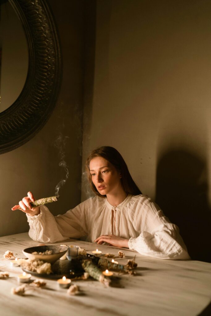 A serene moment of a woman performing a mystical ritual with incense smoke indoors.
